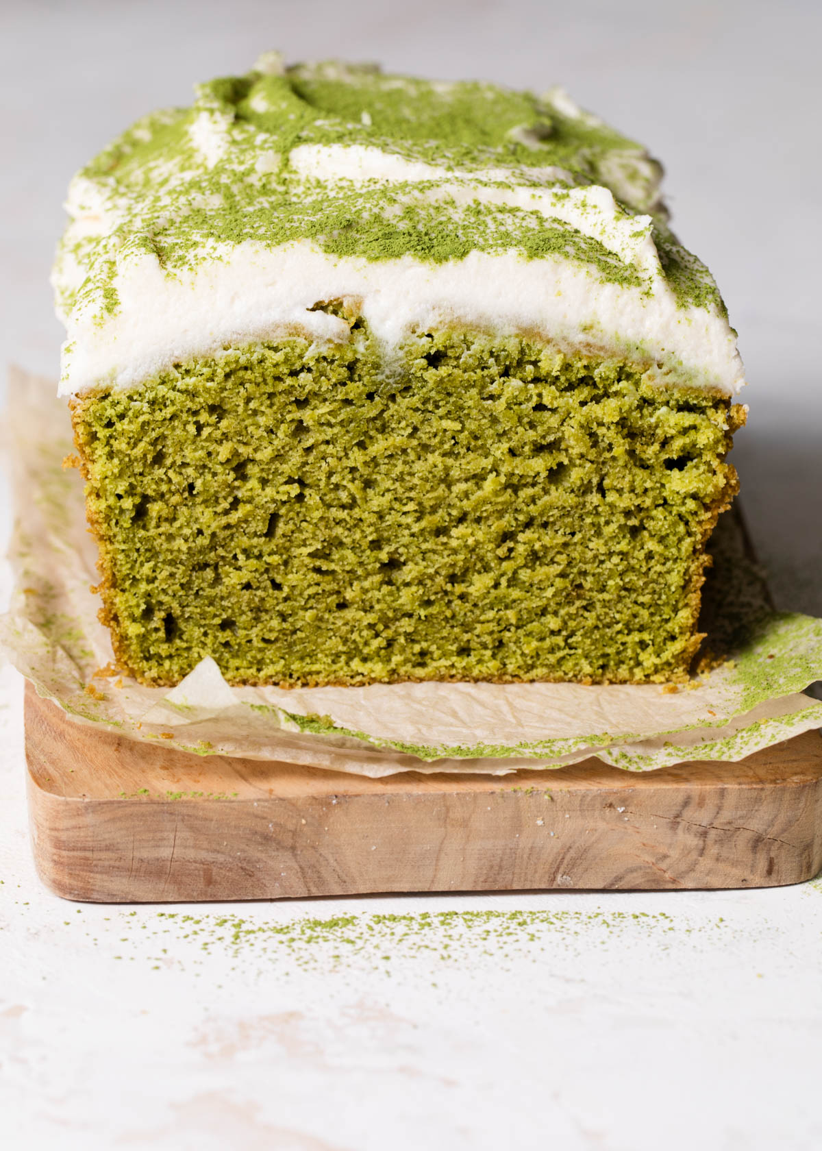 A cross-section of a matcha cake loaf with coconut frosting on top