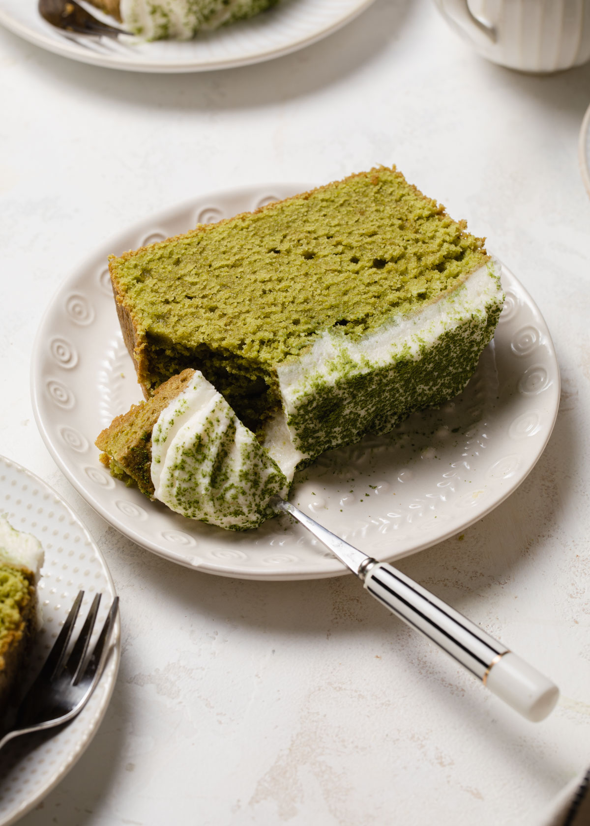A slice matcha cake with coconut frosting on top