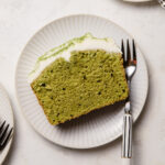 A slice of matcha pound cake with coconut frosting on top of a white plate