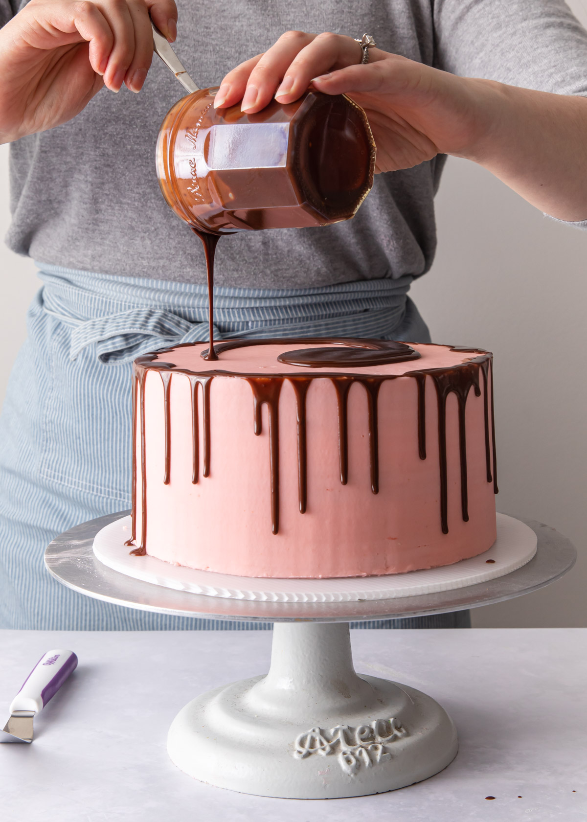 Pouring chocolate glaze on the top of a drip cake