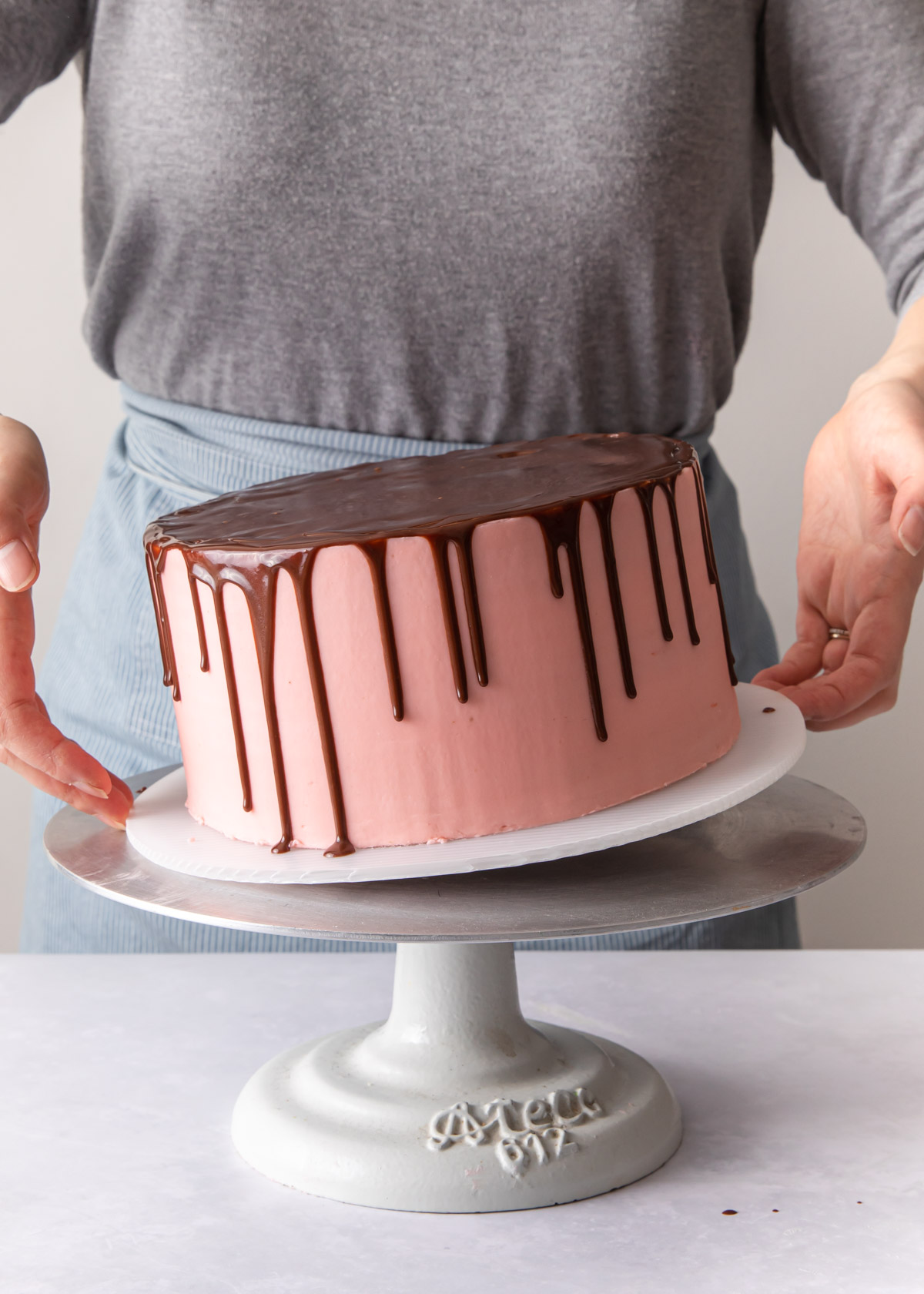 Tapping the bottom of a drip cake with pop any air bubbles in the glaze