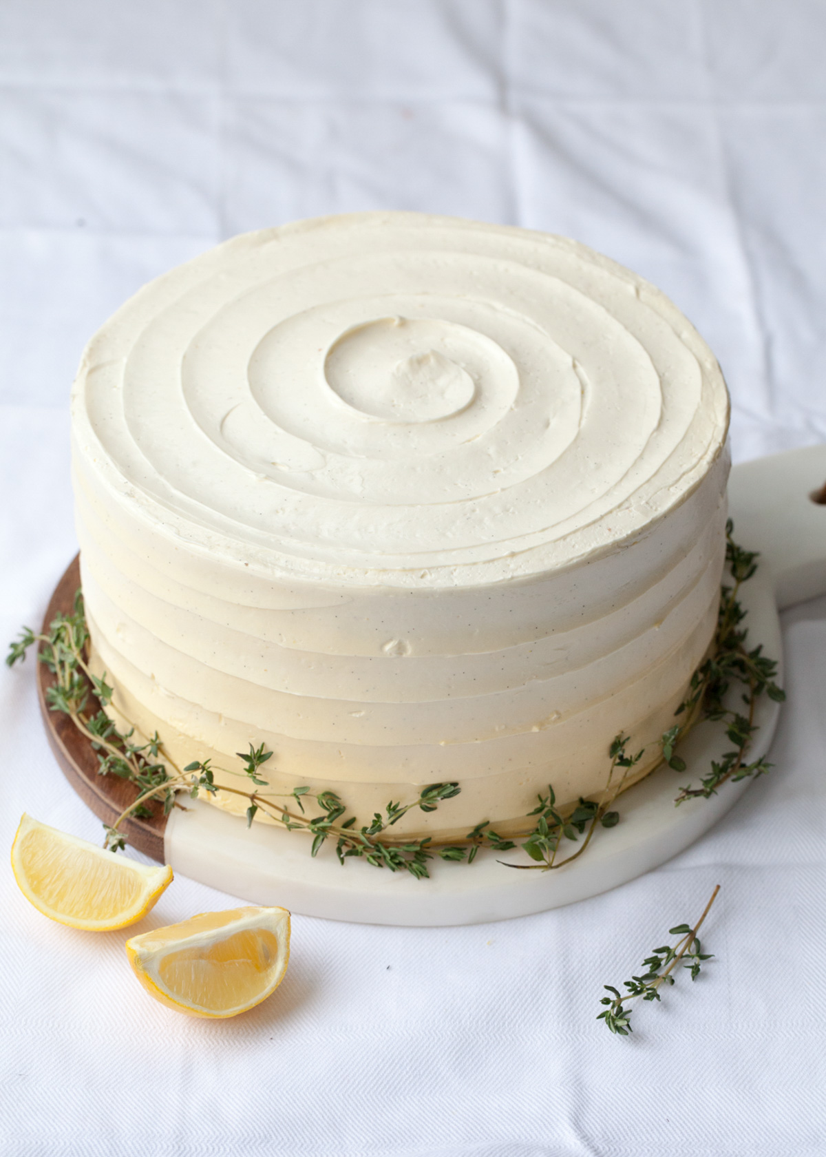 Lemon thyme cake with swirled yellow buttercream frosting and fresh thyme