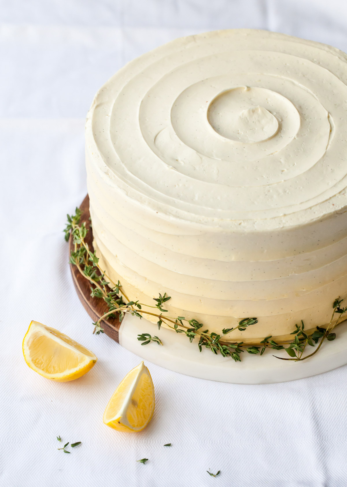 Lemon thyme cake with swirled yellow buttercream frosting and fresh thyme
