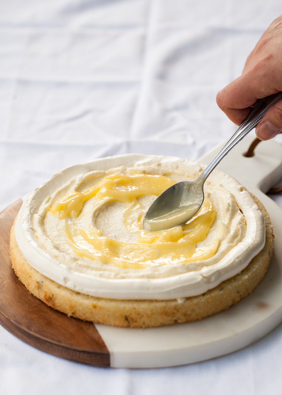 Swirling lemon curd in the filling of a lemon thyme cake