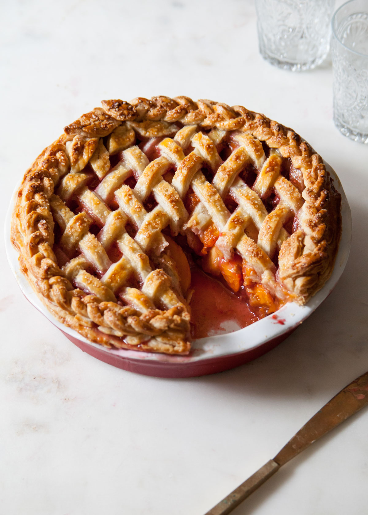 An apricot pie with raspberries and a lattice crust that has been sliced open.