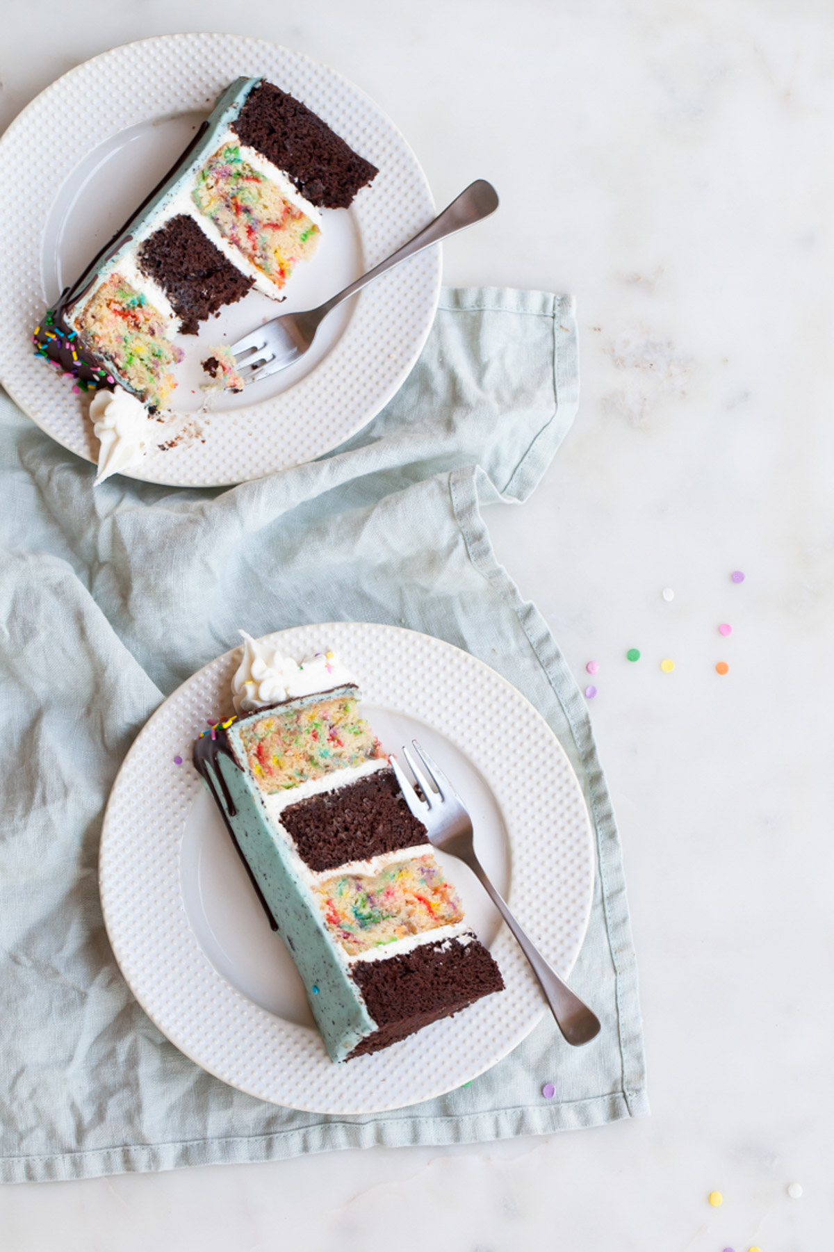 Slices of oreo confetti cake with alternating layers of chocolate and sprinkle cake