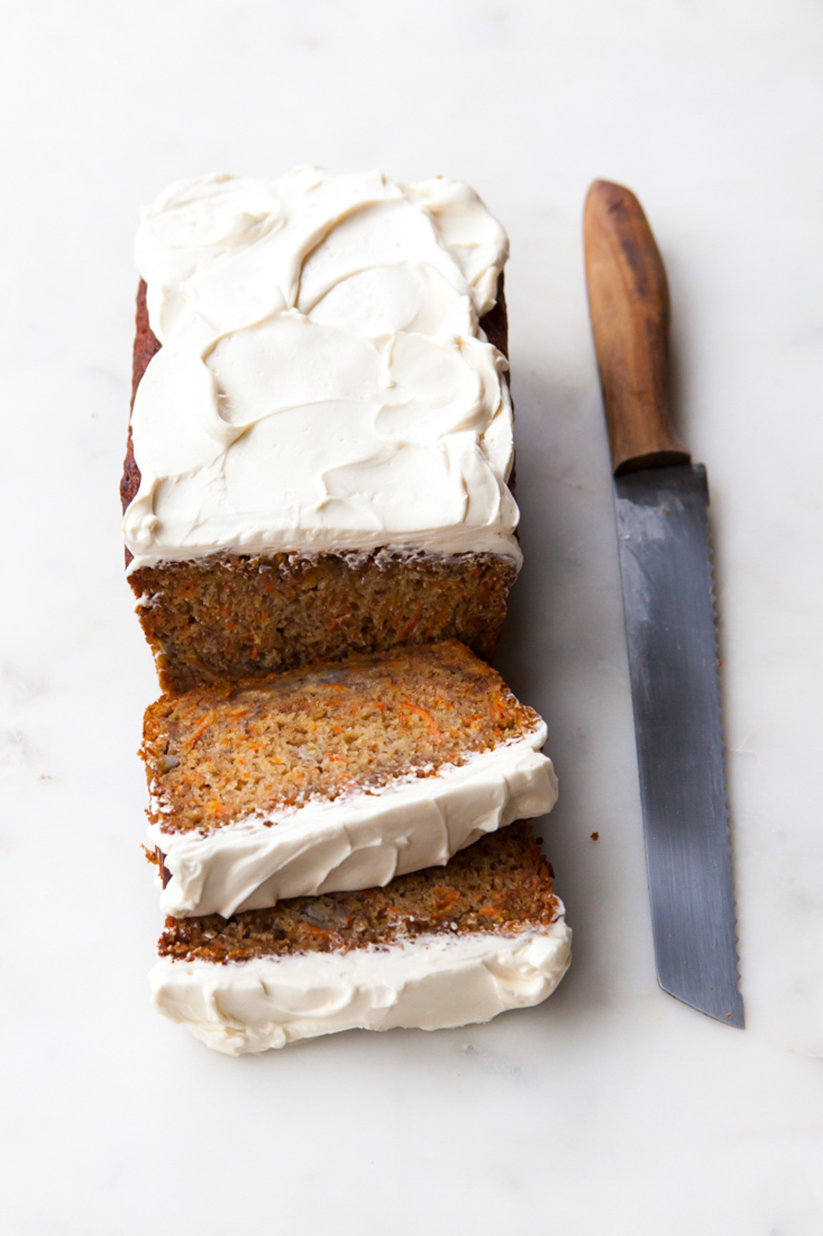 A load of carrot banana bread with cream cheese frosting on top that's been sliced