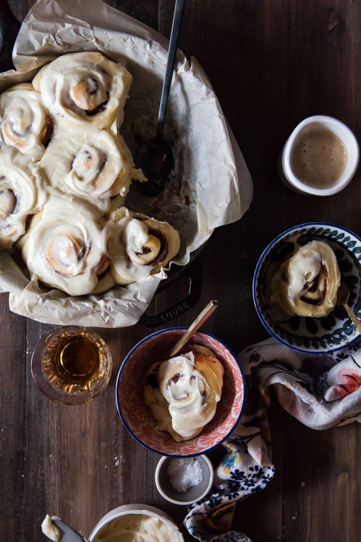 Date cinnamon rolls with  bourbon cream cheese being served out of a cast iron pan