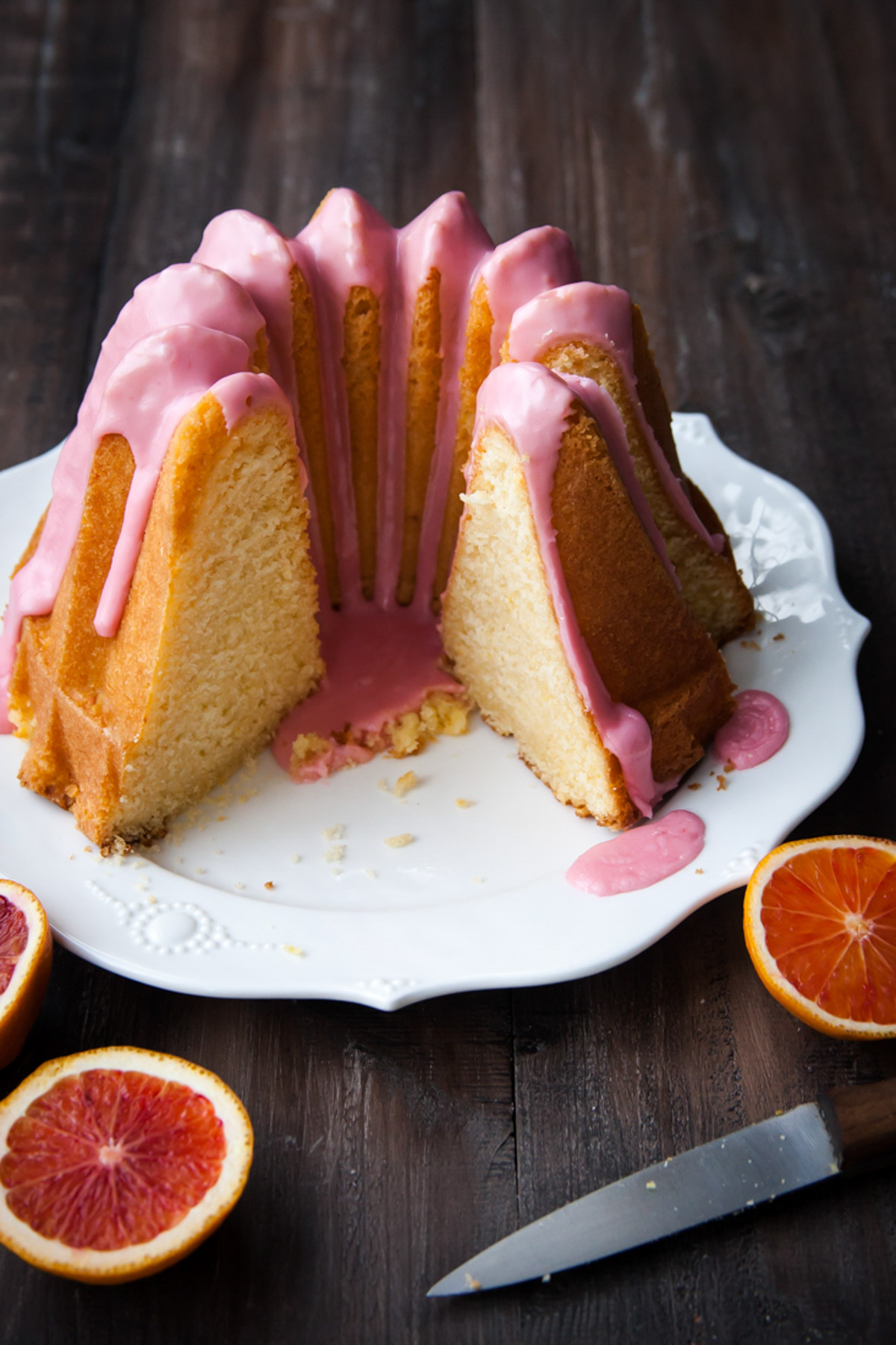 An orange bundt cake that's been sliced on a white platter