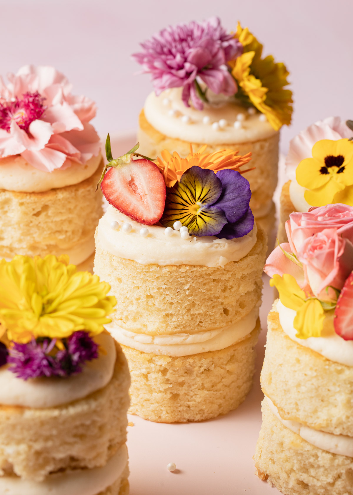 A bunch of mini two-layer vanilla cakes with flowers on top