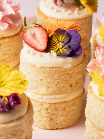 A bunch of mini two-layer vanilla cakes with flowers on top