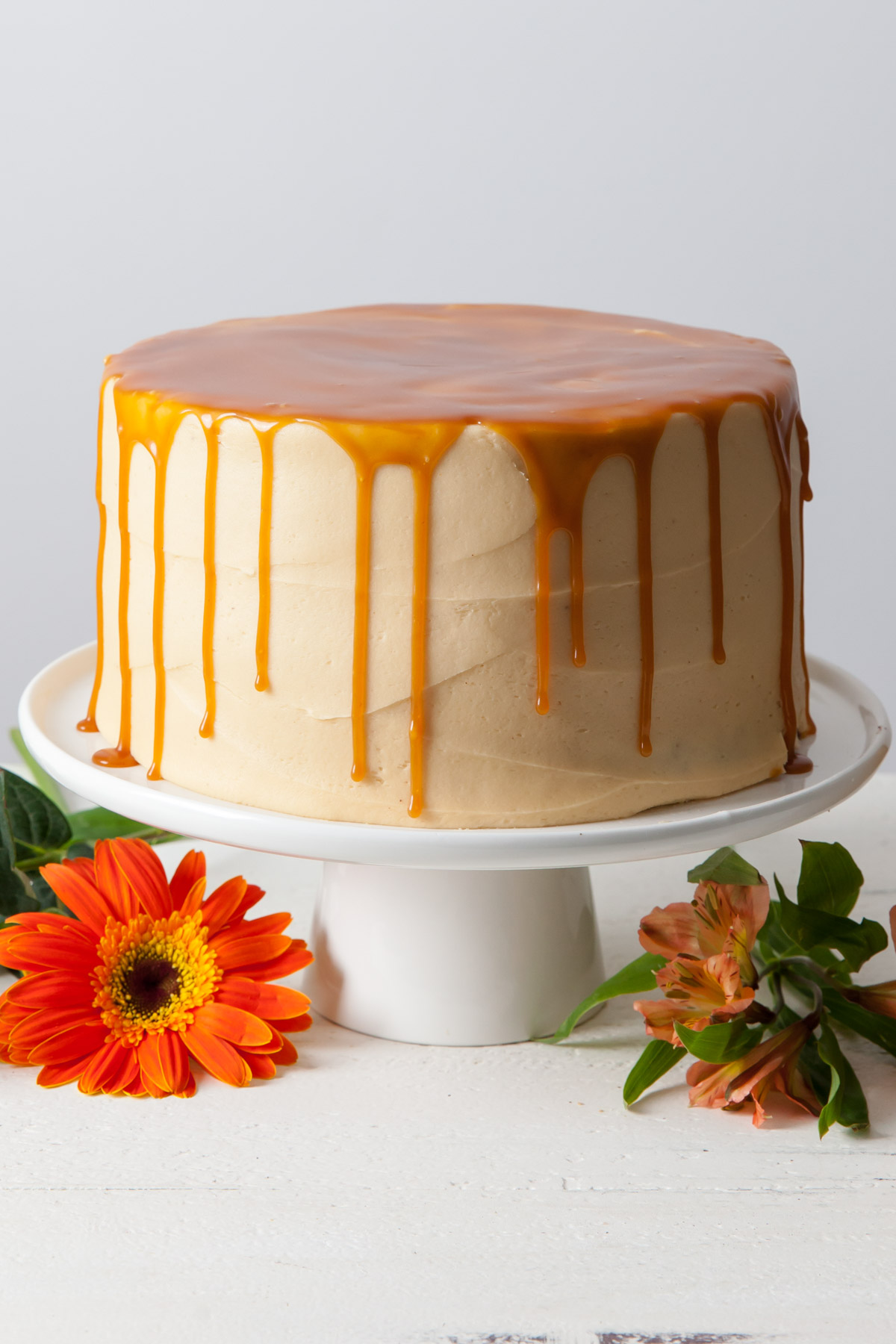 A chocolate layer cake with caramel frosting and a caramel drip on top.