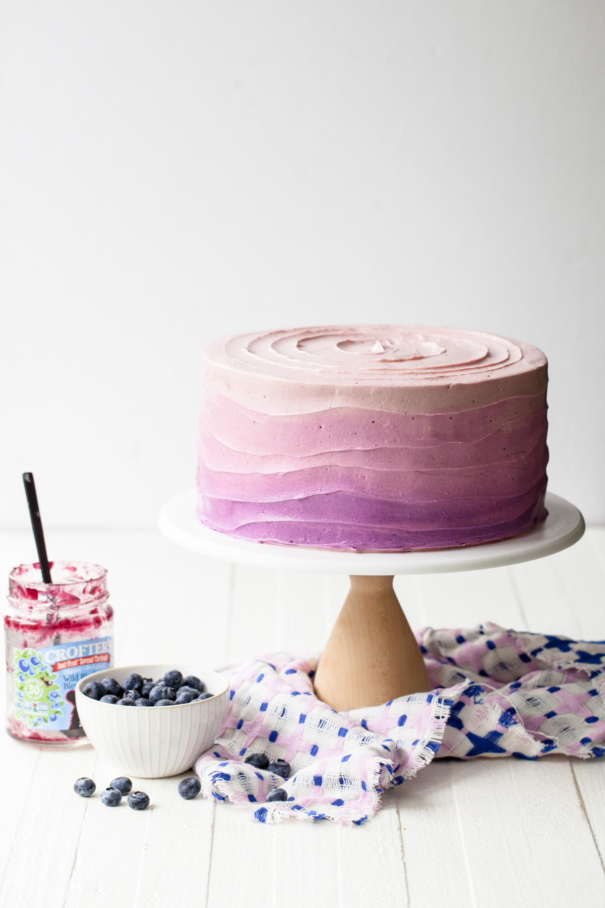 A blueberry layer cake with purple ombre icing on a cake stand