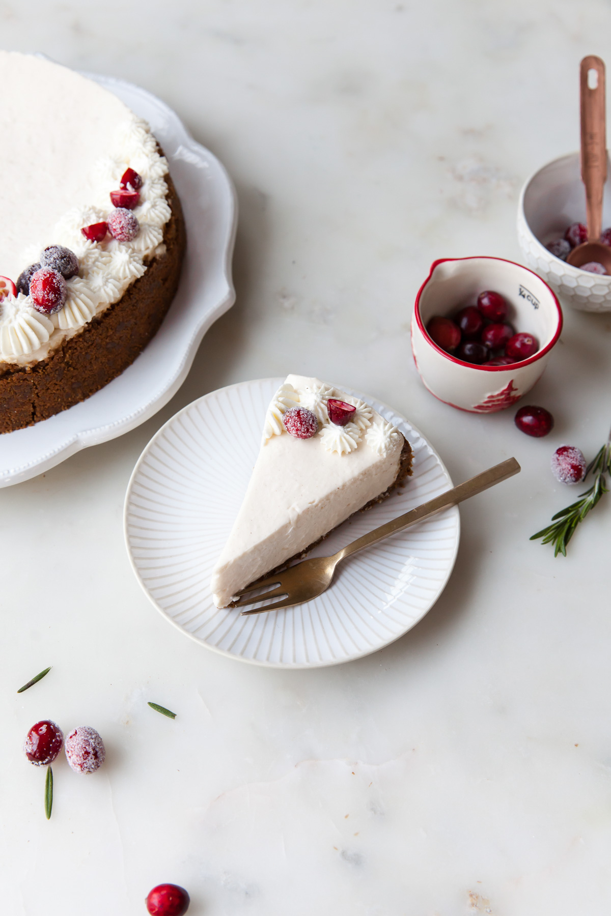 A slice of eggnog cheesecake topped with whipped cream and sugared cranberries
