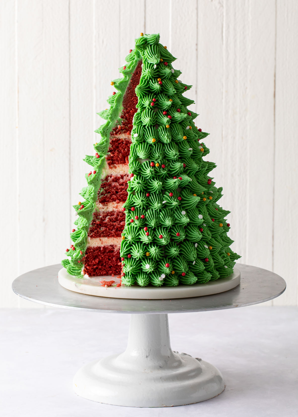 A red velvet cake carved and decorated to look like a 3D Christmas Tree 
