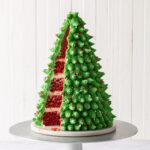 A 3D Christmas tree cake that is made of red velvet cake and green buttercream