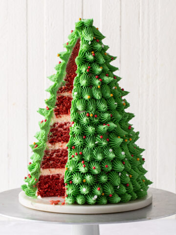 A 3D Christmas tree cake that is made of red velvet cake and green buttercream