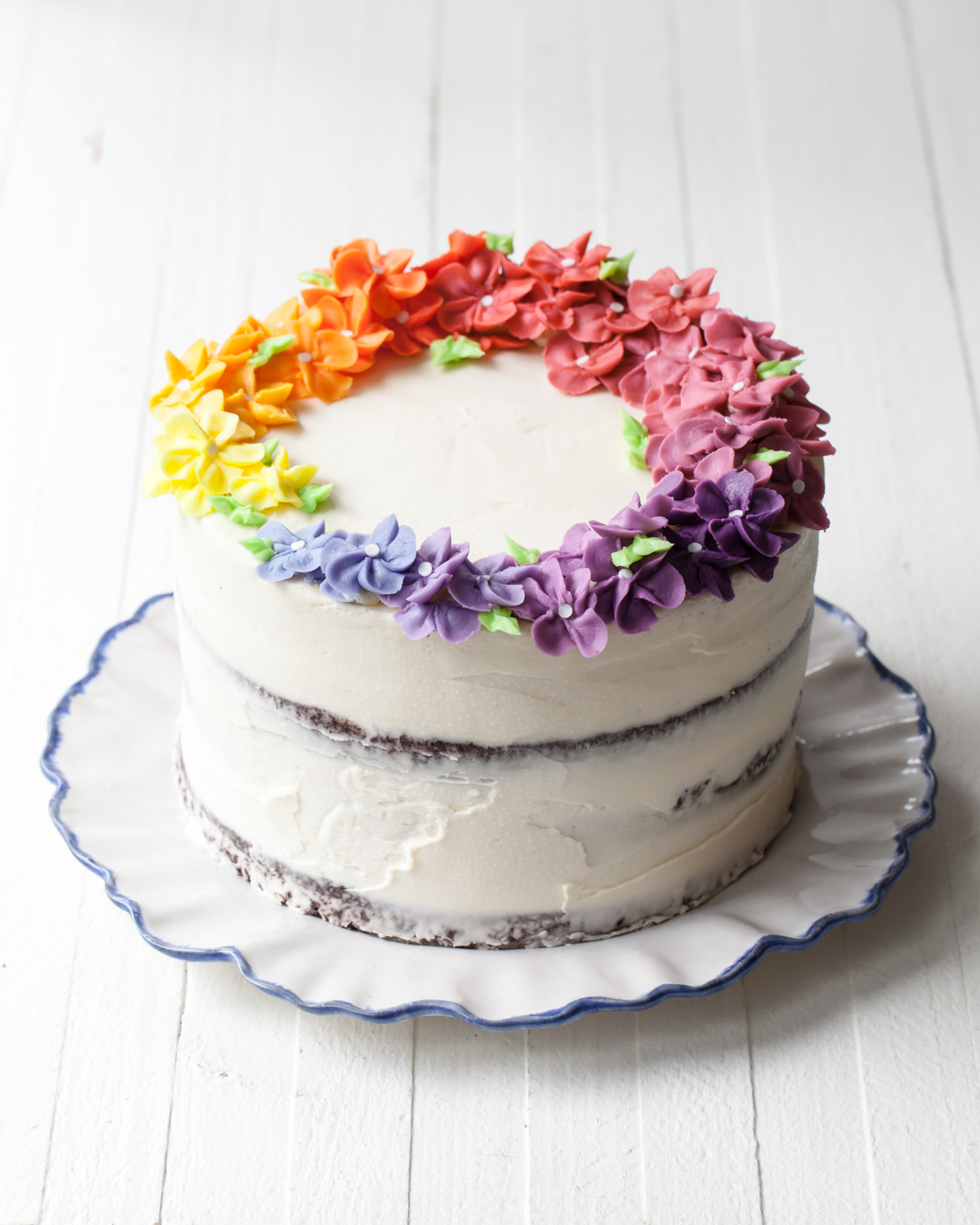 Rainbow flower cake with piped flowers around the top