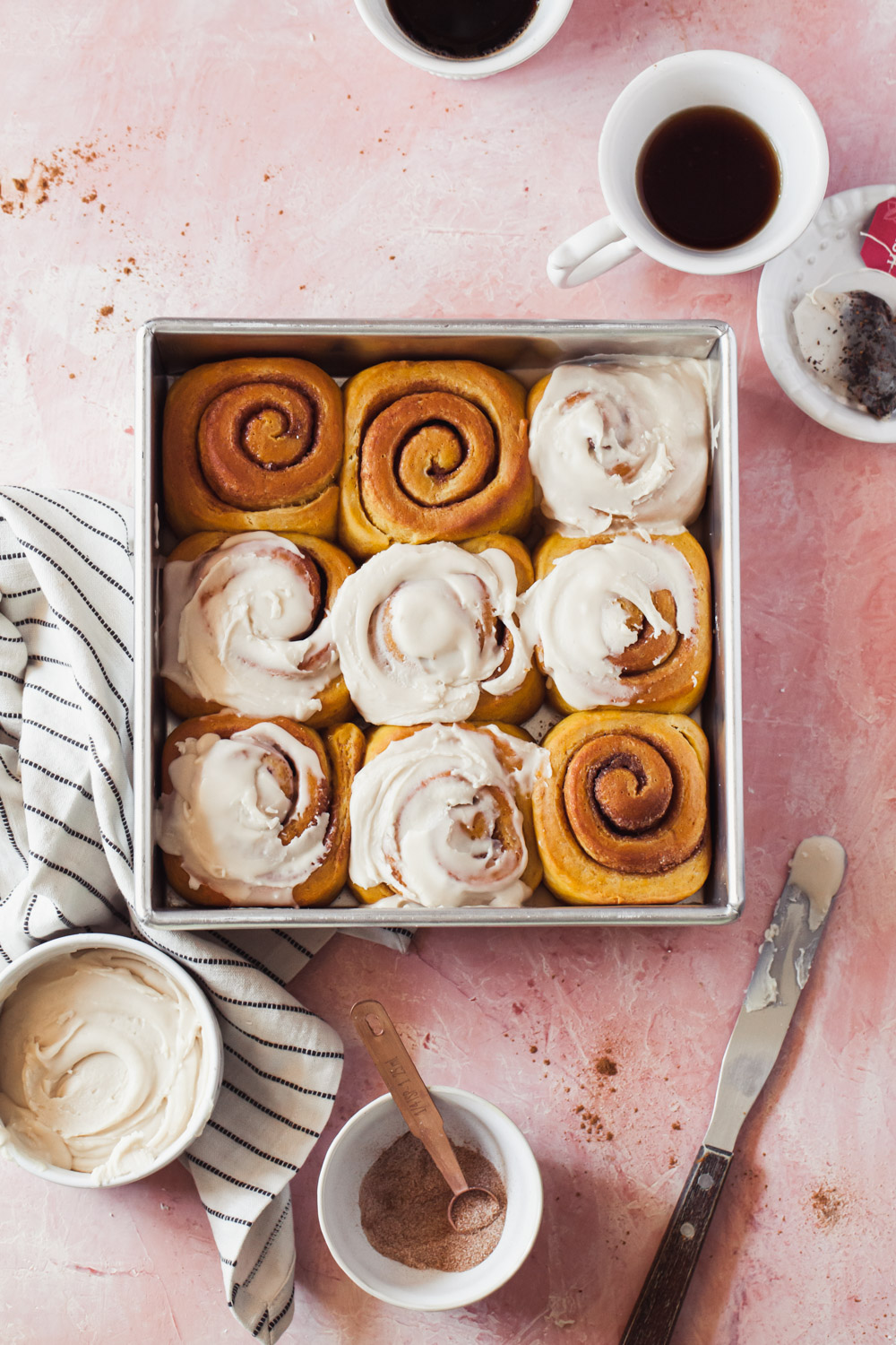 Pumpkin cinnamon rolls in the pan with swirls of vanilla chai glaze