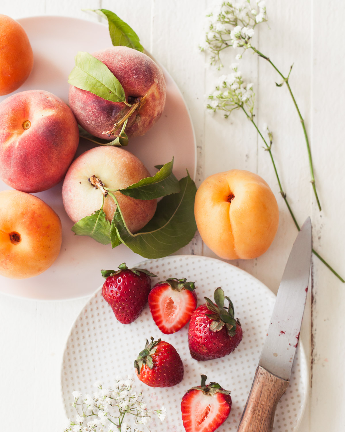 Fresh summer peaches and strawberries on a white table