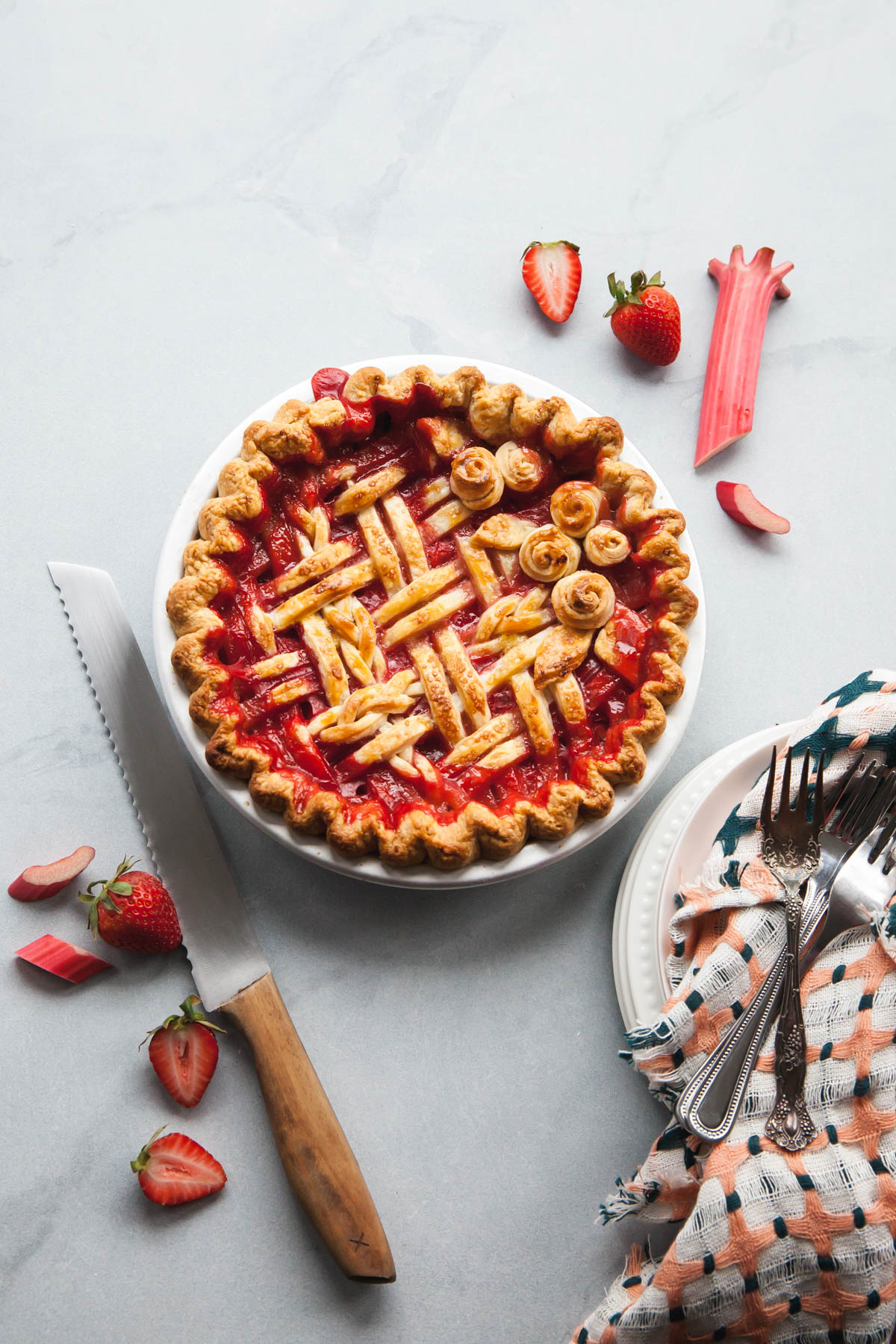 A baked strawberry rhubarb pie with jammy red filling in an all butter crust