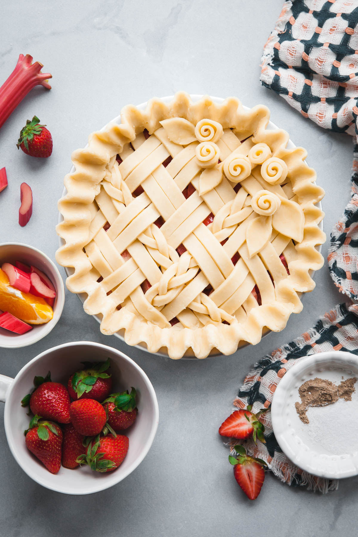 An unbaked strawberry rhubarb pie with a braided lattice and hints of orange zest.