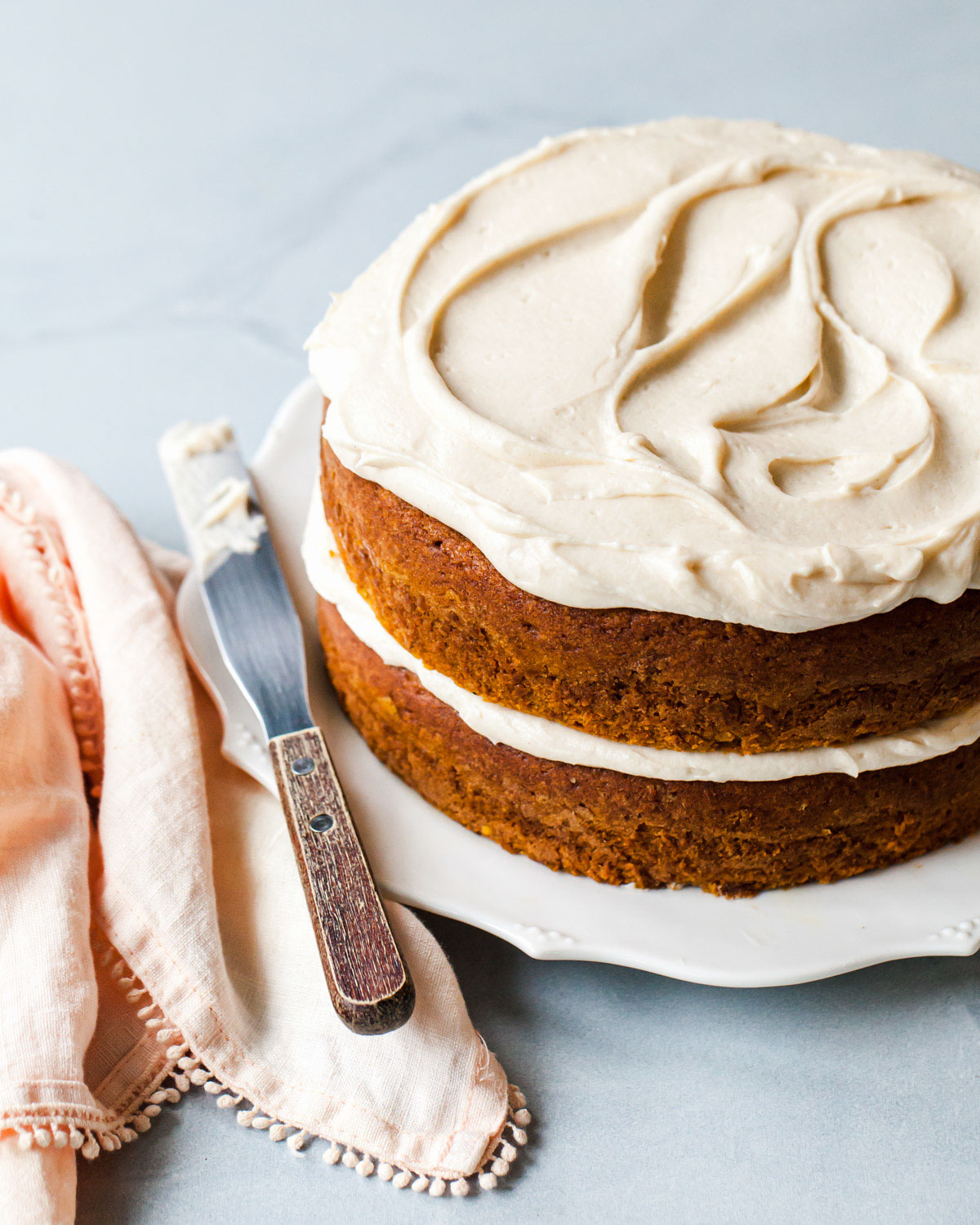 A two-layer pumpkin cake with maple cream cheese frosting swirled on top