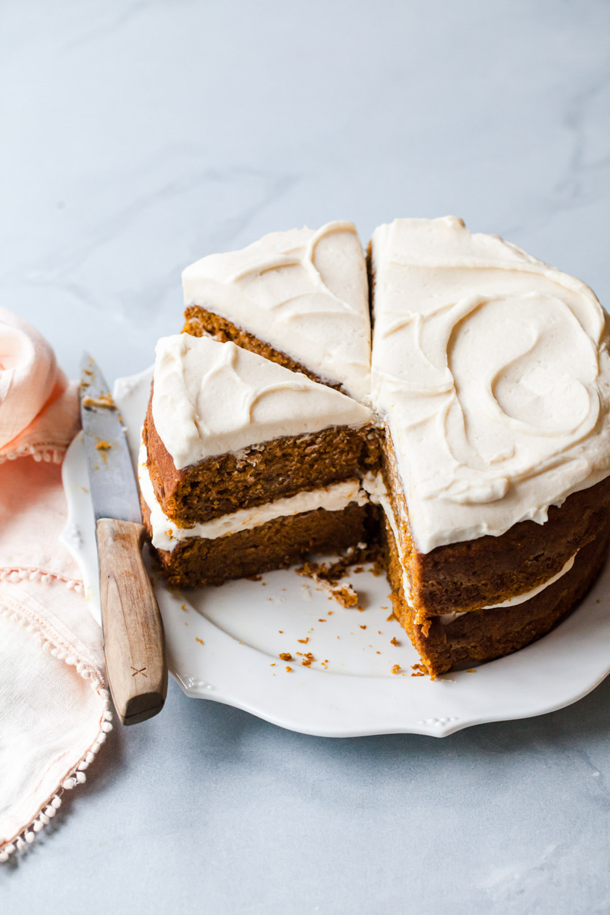 the best pumpkin cake recipe with maple cream cheese frosting sliced on a platter