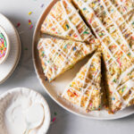 A birthday coffee cake with sprinkles and vanilla glaze on top.