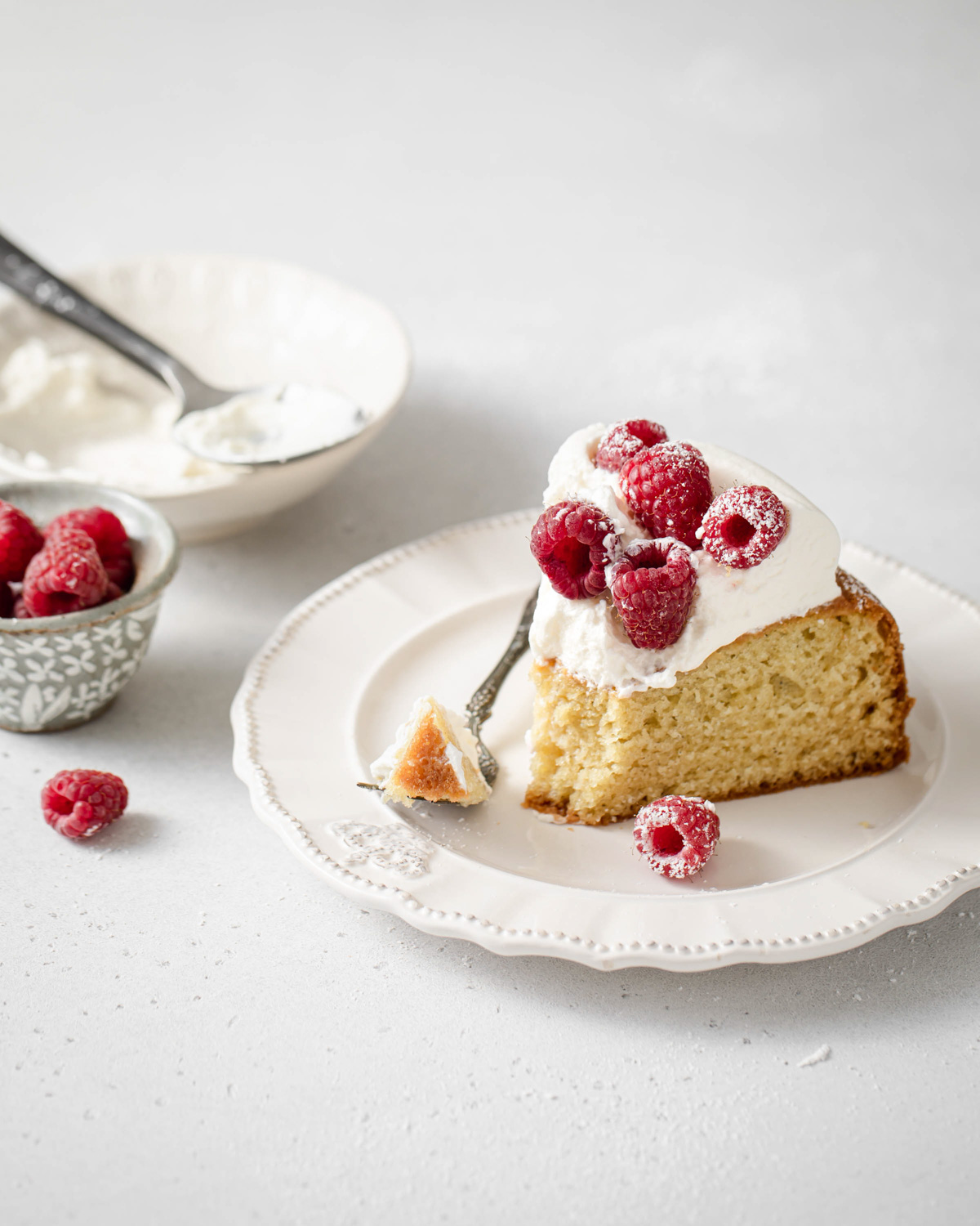 A slice of greek yogurt cake with whipped cream and raspberries