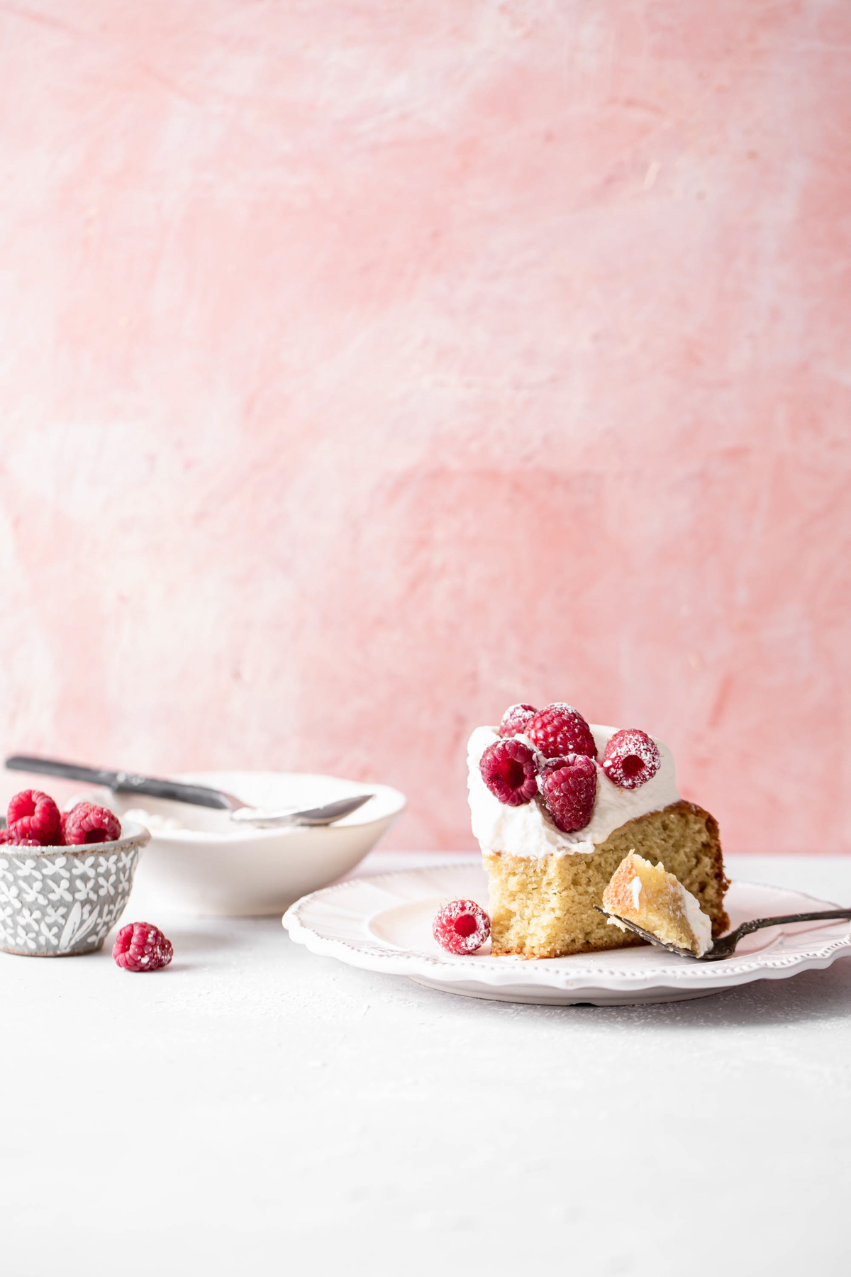 A slice of greek yogurt cake with whipped cream and raspberries