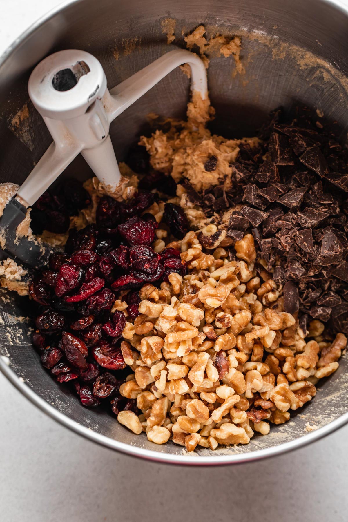 Cranberries, walnuts, and chocolate being added to oatmeal cookie dough