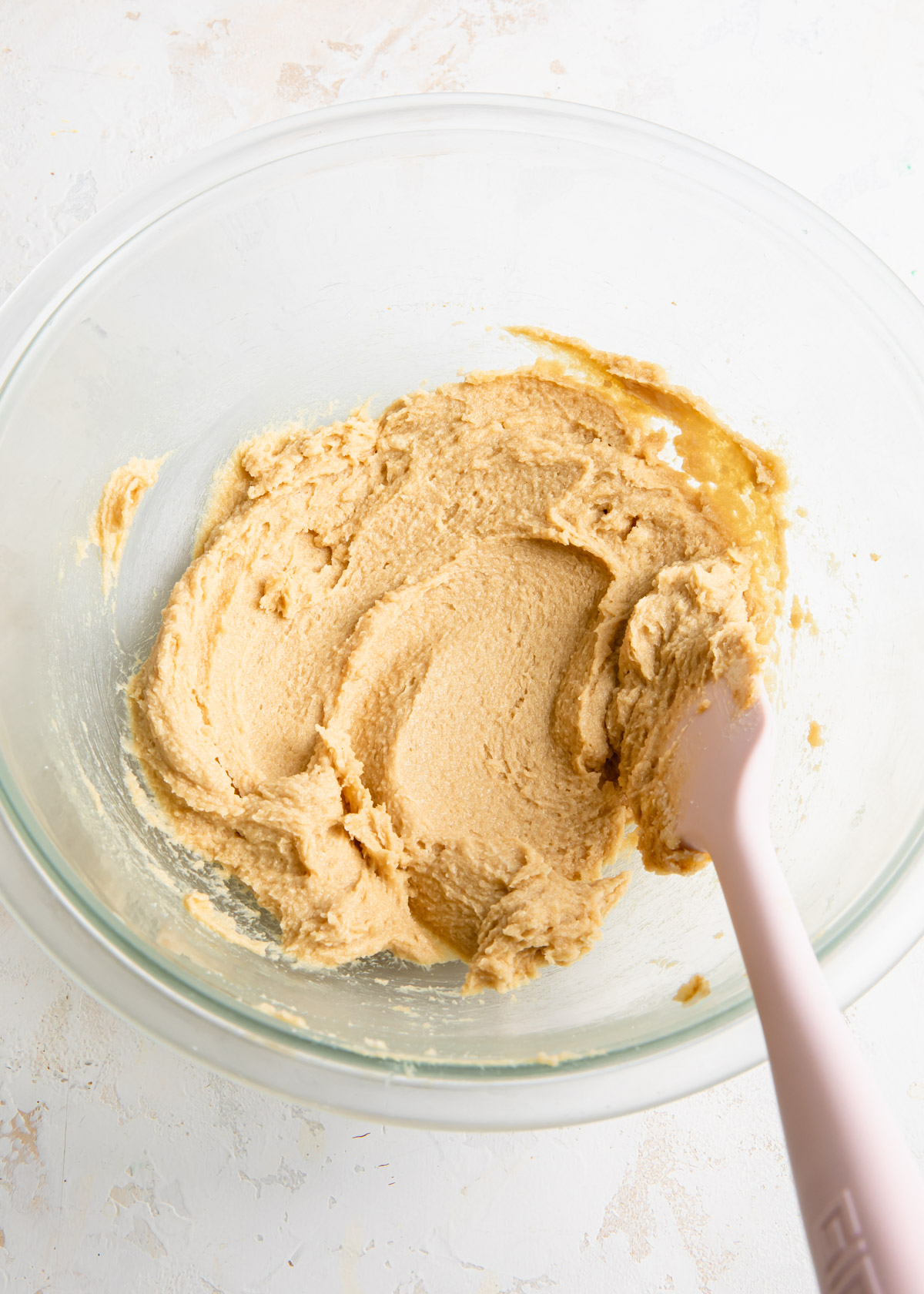 Soft butter, granulated sugar, and brown sugar being stirred together
