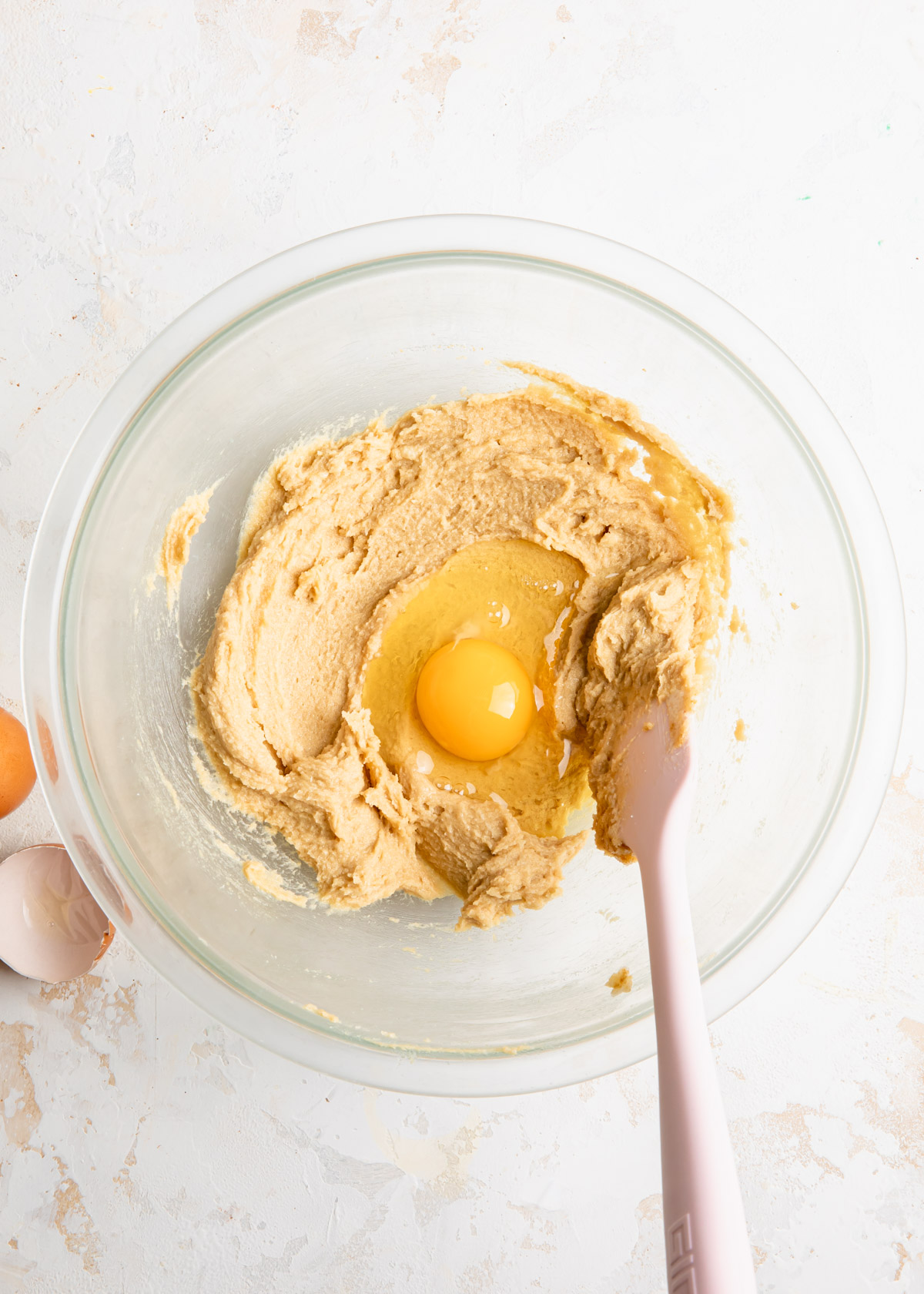 Adding an egg to creamed butter and sugar for cookie dough
