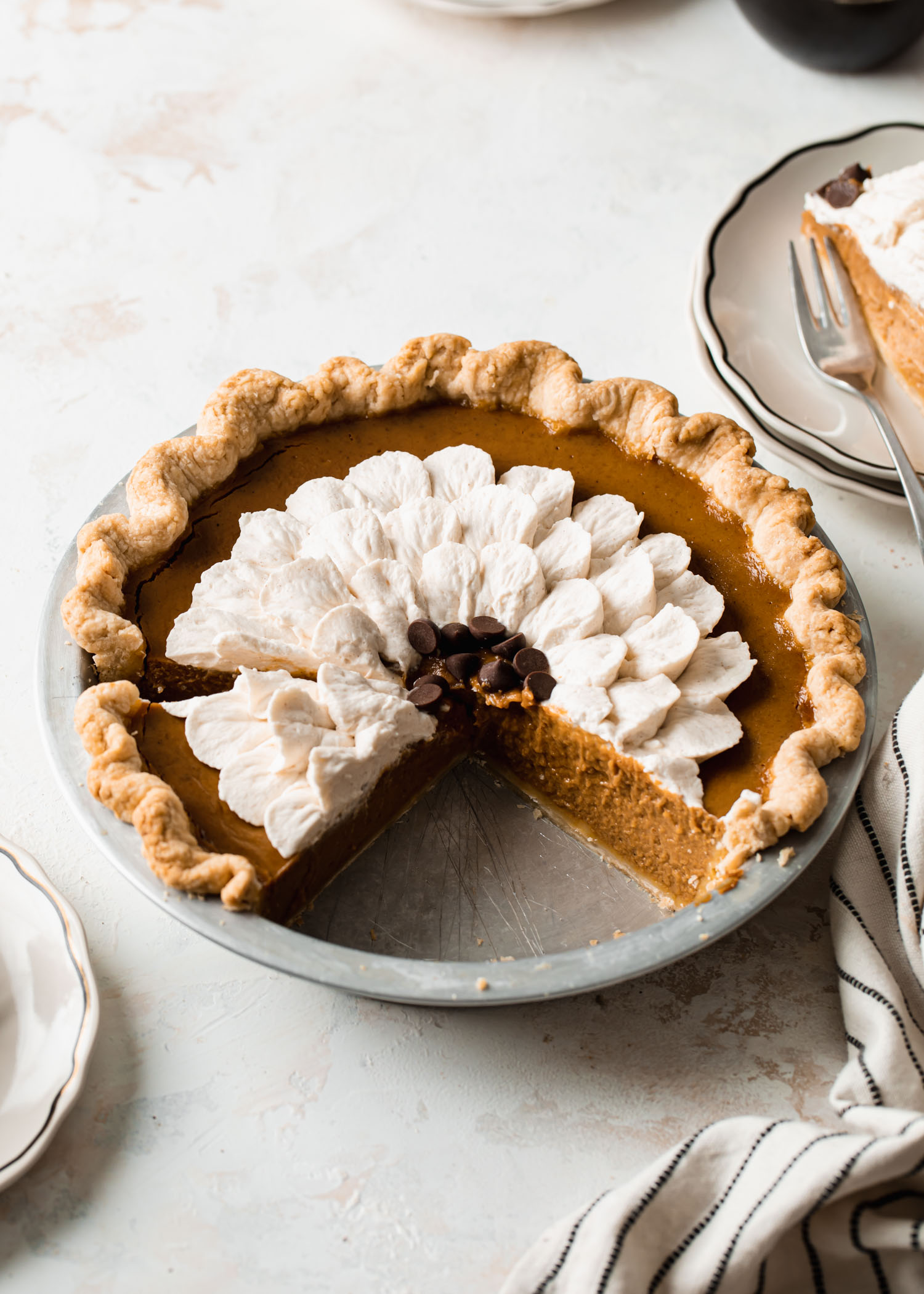 A slice pumpkin pie with cinnamon whipped cream on top