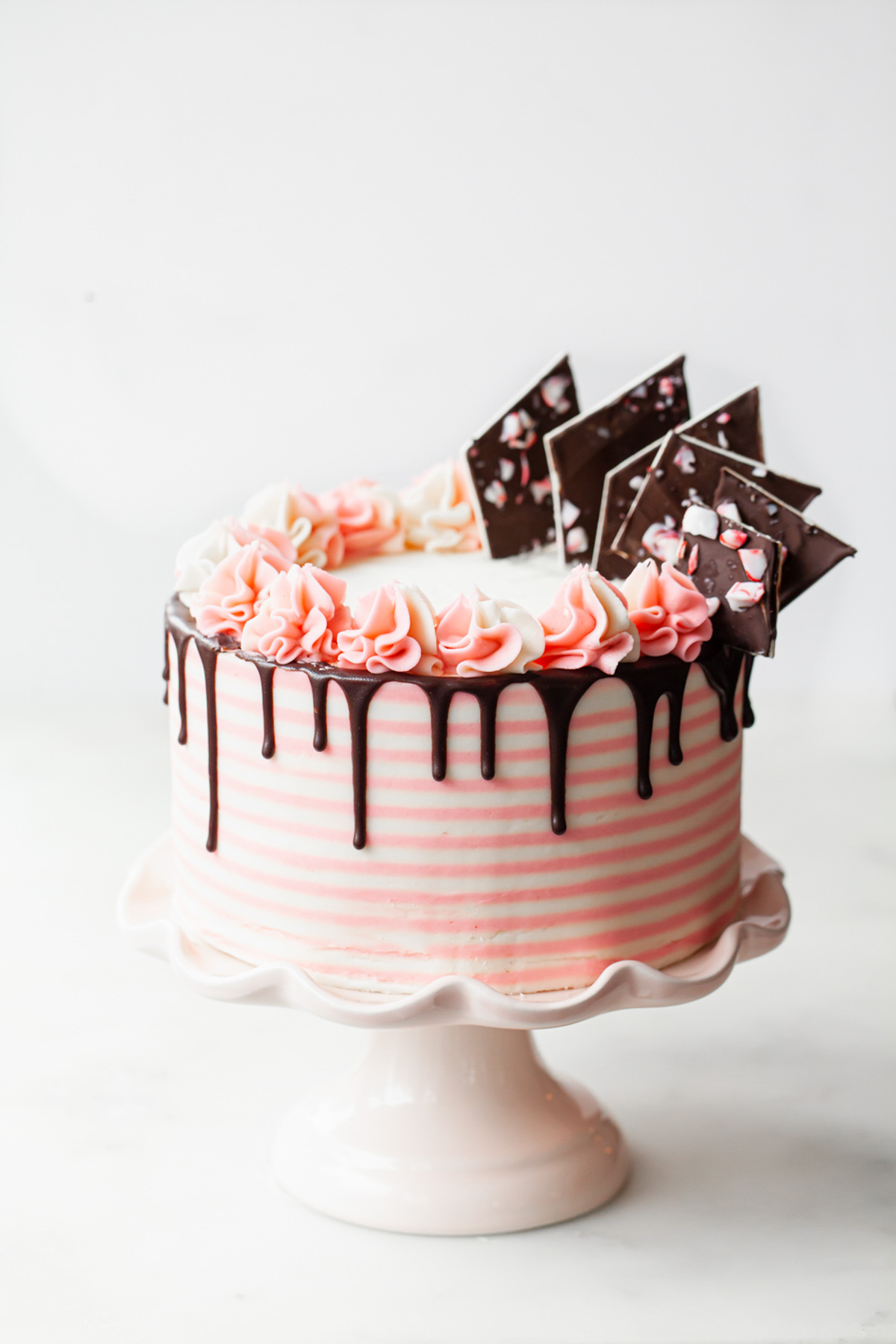 Chocolate peppermint cake with pink and white candy cane stripes with chocolate drip and peppermint bark on top