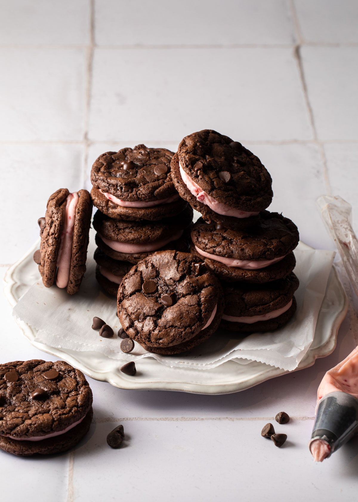 A pile of chocolate peppermint cookies with pink candy cane buttercream filling