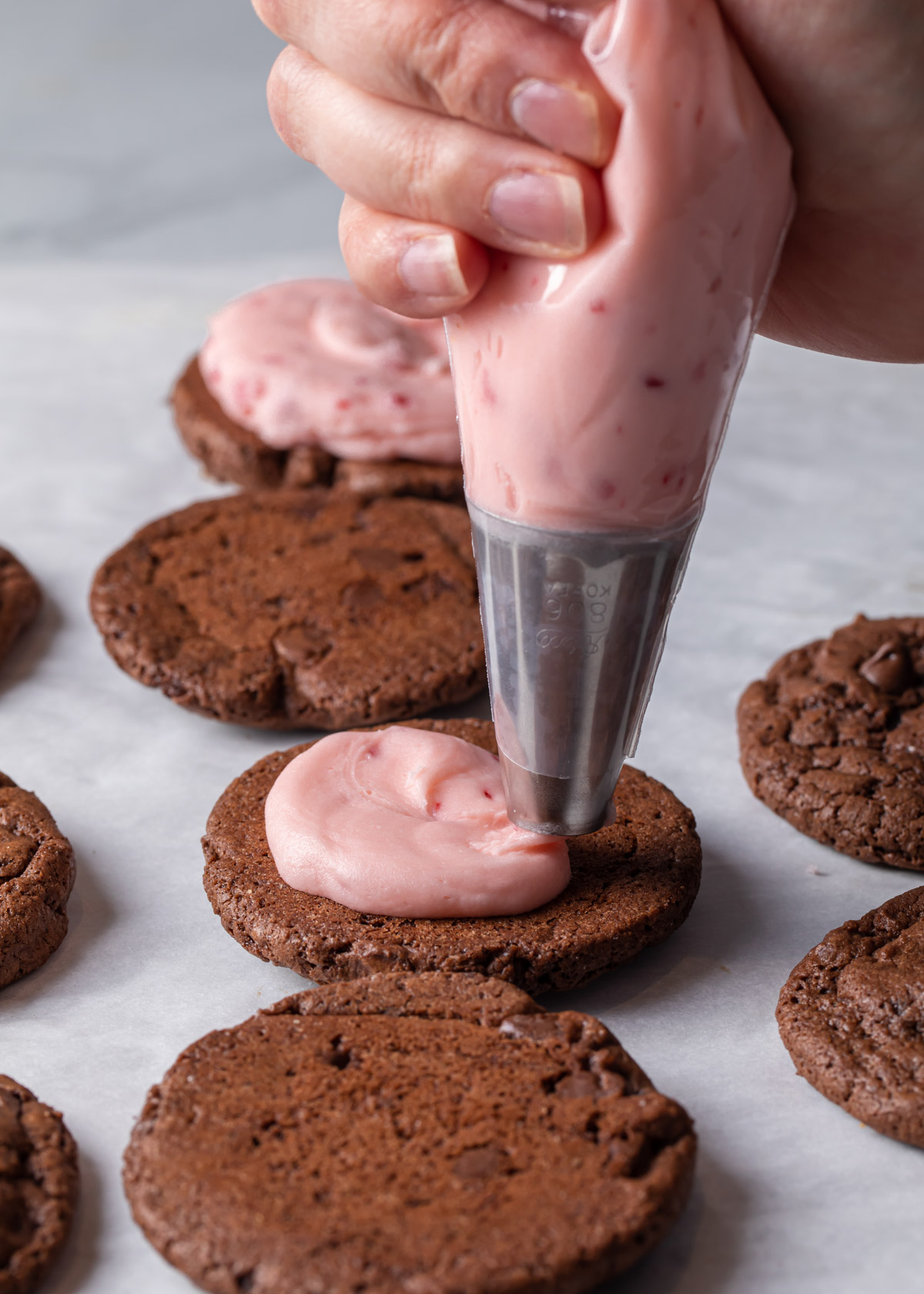 Chocolate cookies being filled with peppermint buttercream filling