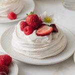 A mini pavlova made with French meringue and topped with whipped cream and fresh berries