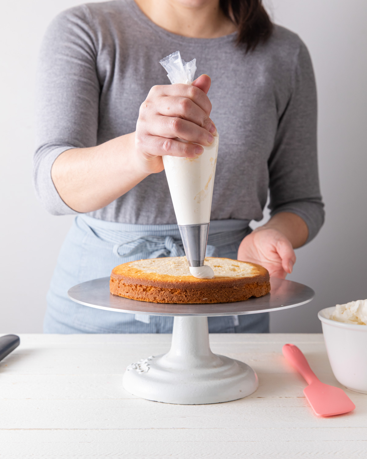 Piping buttercream filling on a cake