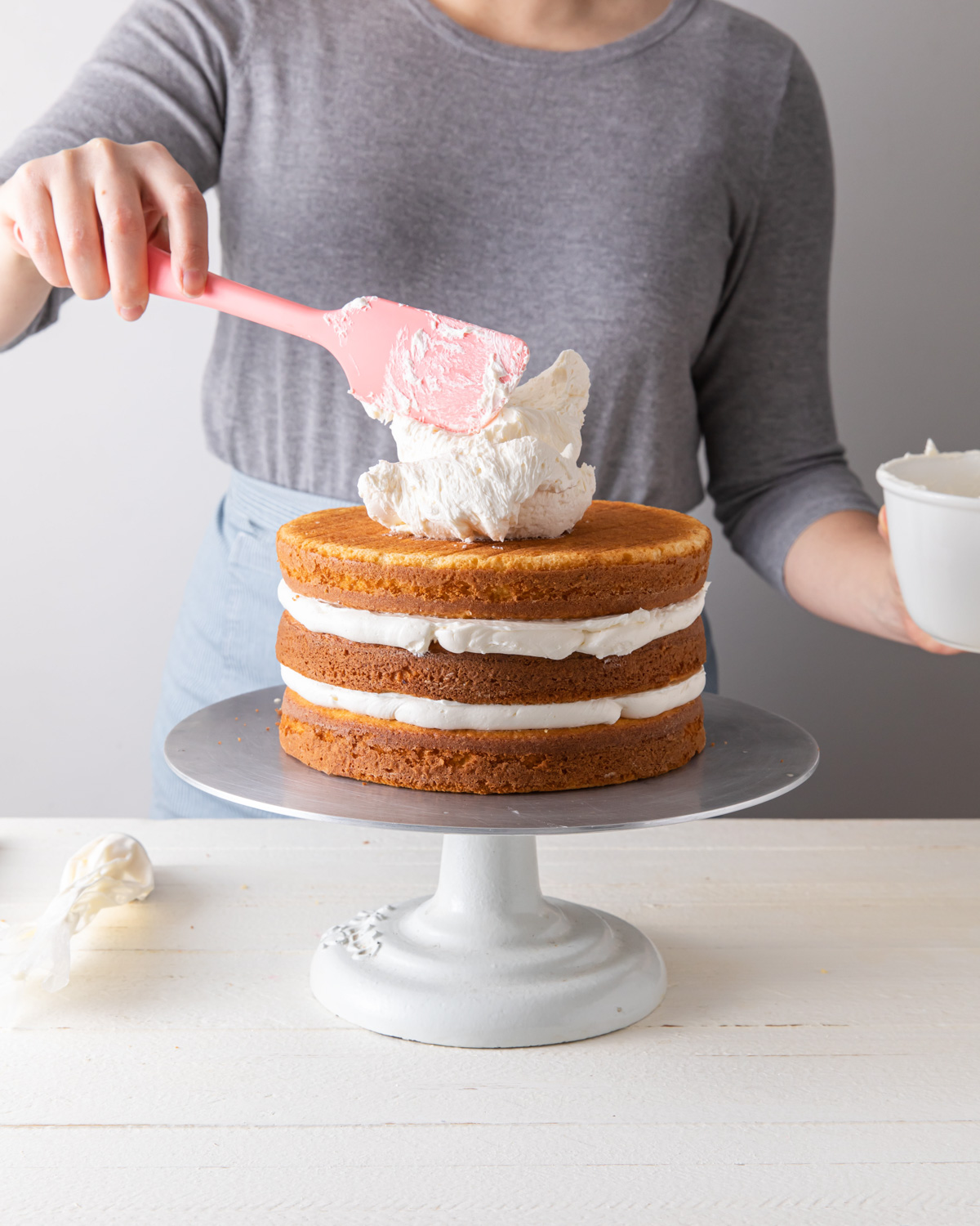 Adding frosting to the top of a stacked layer cake