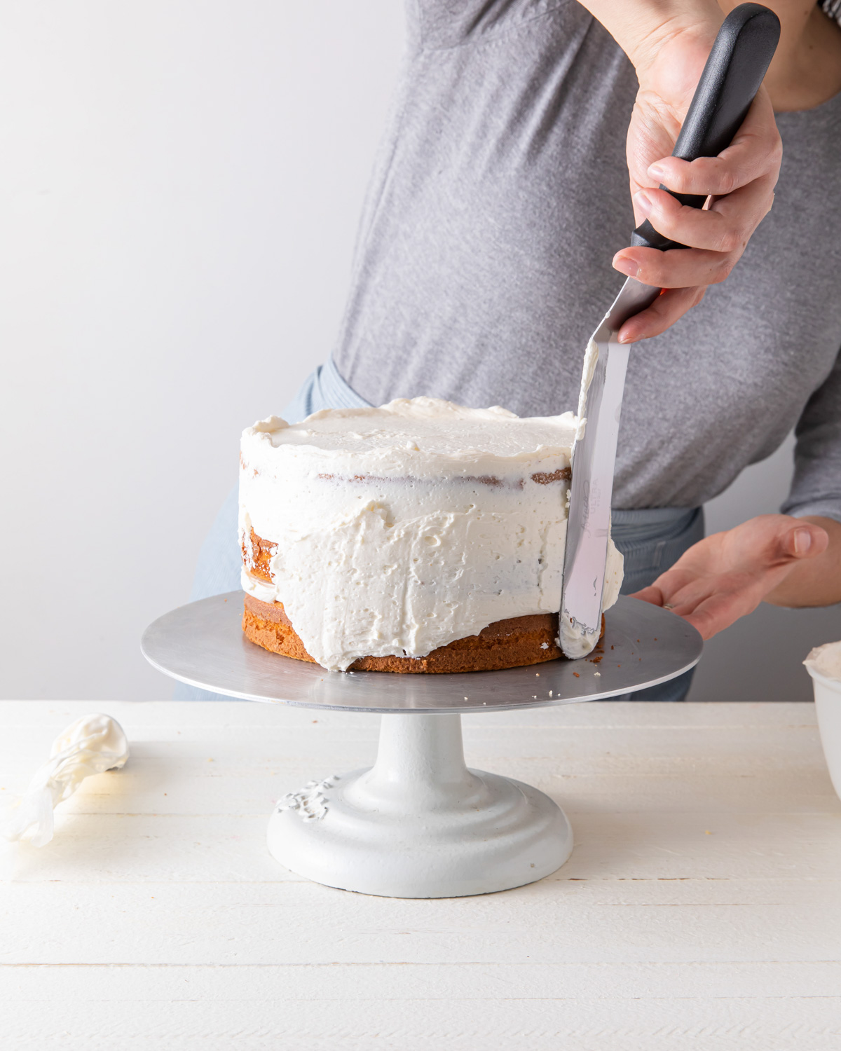 Spreading the crumb coat on a layer cake