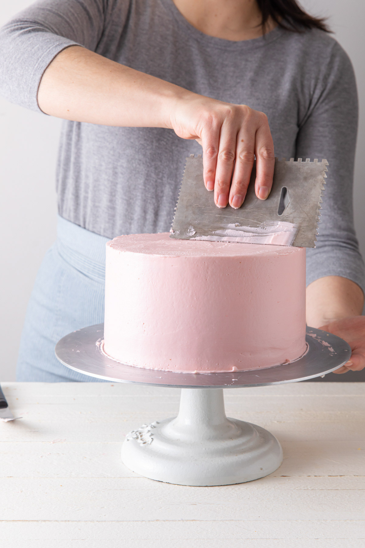 Smothing out the top of a frosted cake with an icing smoother