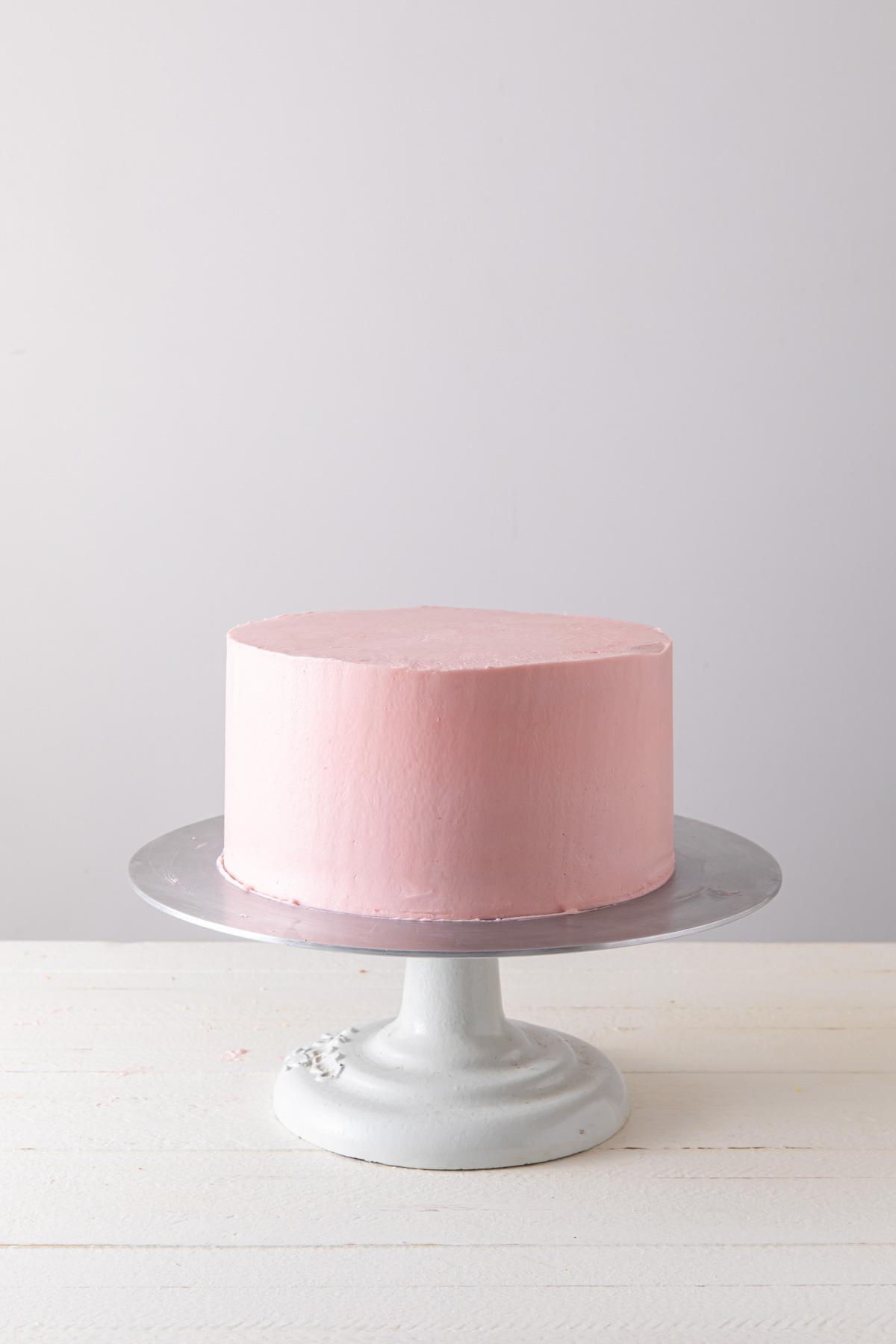 A smoothly frosted cake with pink Swiss meringue buttercream