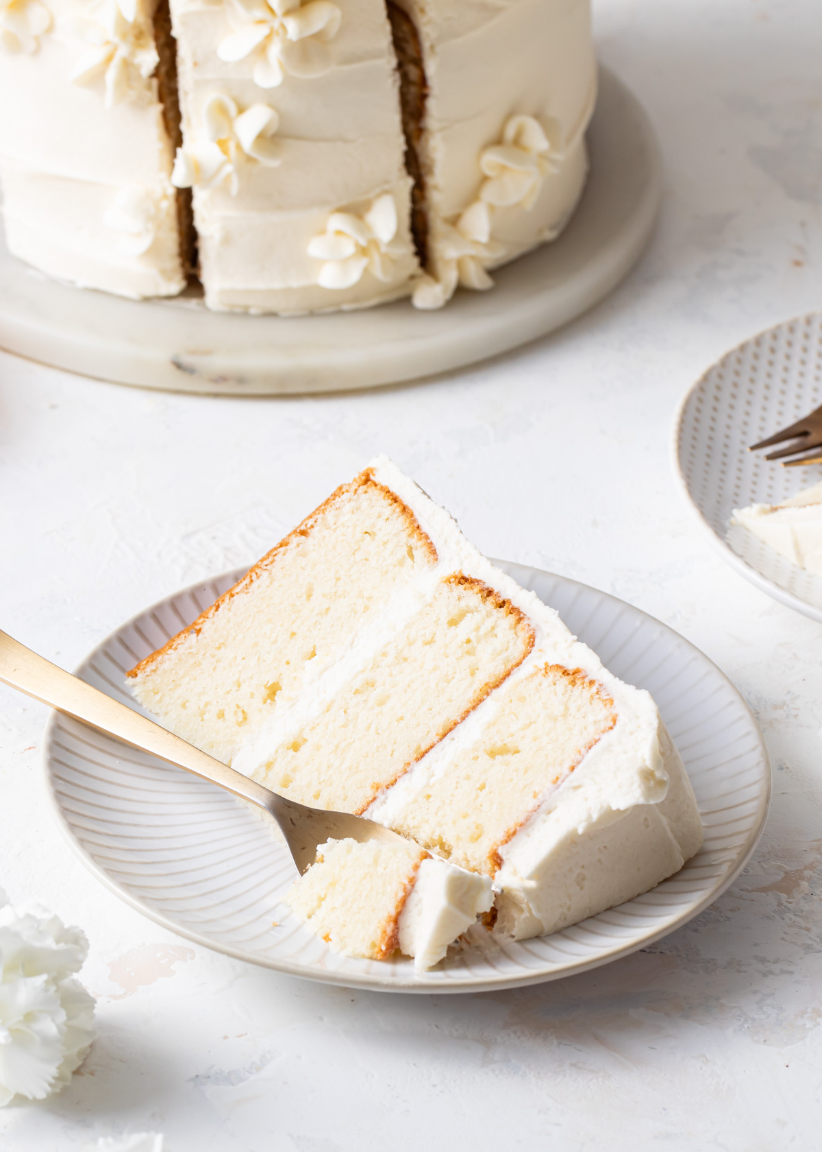 A slice of vanilla layer cake with whipped white chocolate buttercream.