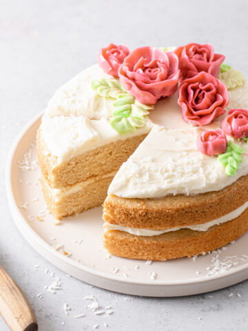 An almond layer cake with cream cheese frosting and buttercream roses on top