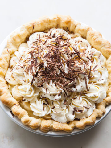 Banana cream pie with piped whipped cream and chocolate shavings on top