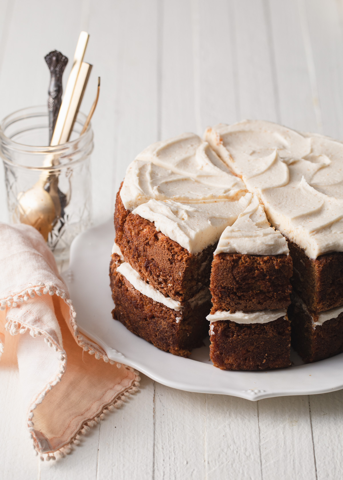 A two-layer carrot cake with brown butter filling and frosting that has been sliced on a platter.