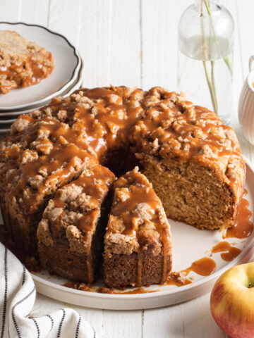 An apple coffee cake baked in a tube pan with dripped caramel sauce over the top