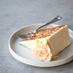 A slice of carrot cake with a buttercream rose on top